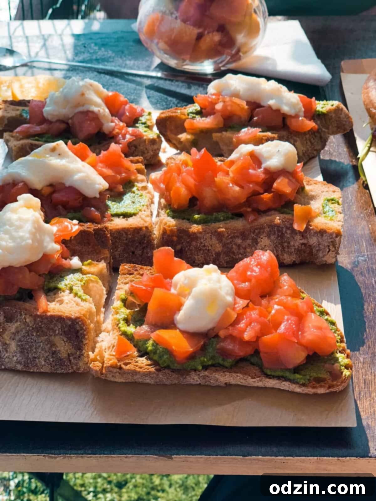 toasted baguette slices with green pesto, diced tomatoes, and cheese