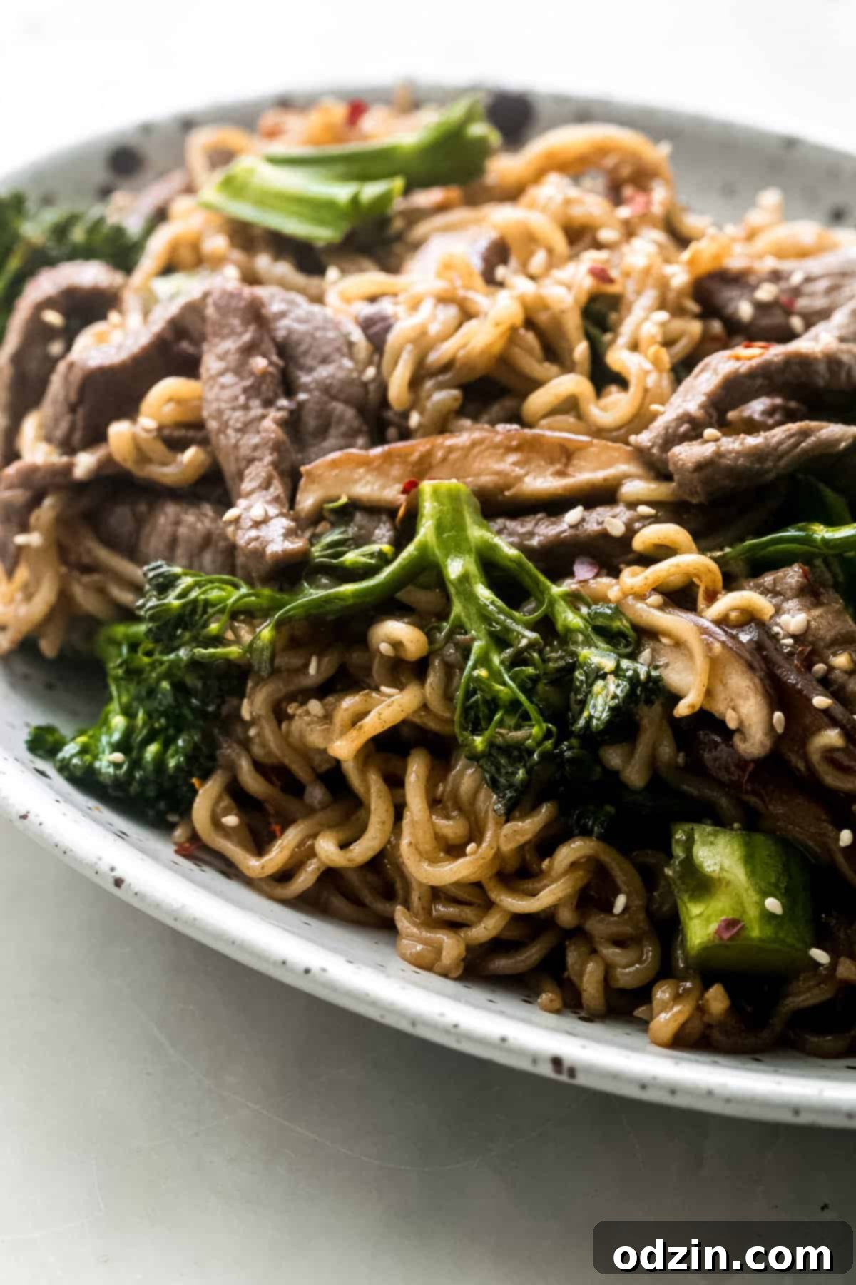 side shot of ramen noodles with beef and broccoli in a rustic bowl