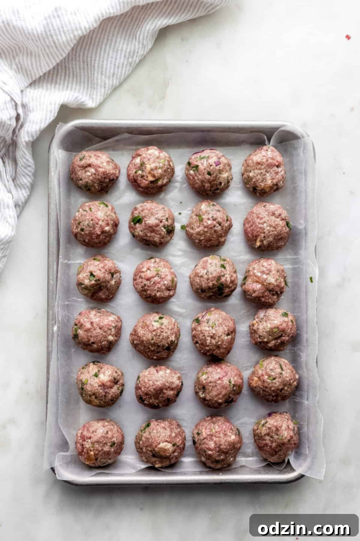 Authentic Greek Keftedes 4 raw, rolled Greek Meatballs (Keftedes) neatly arranged on a baking sheet, ready for cooking