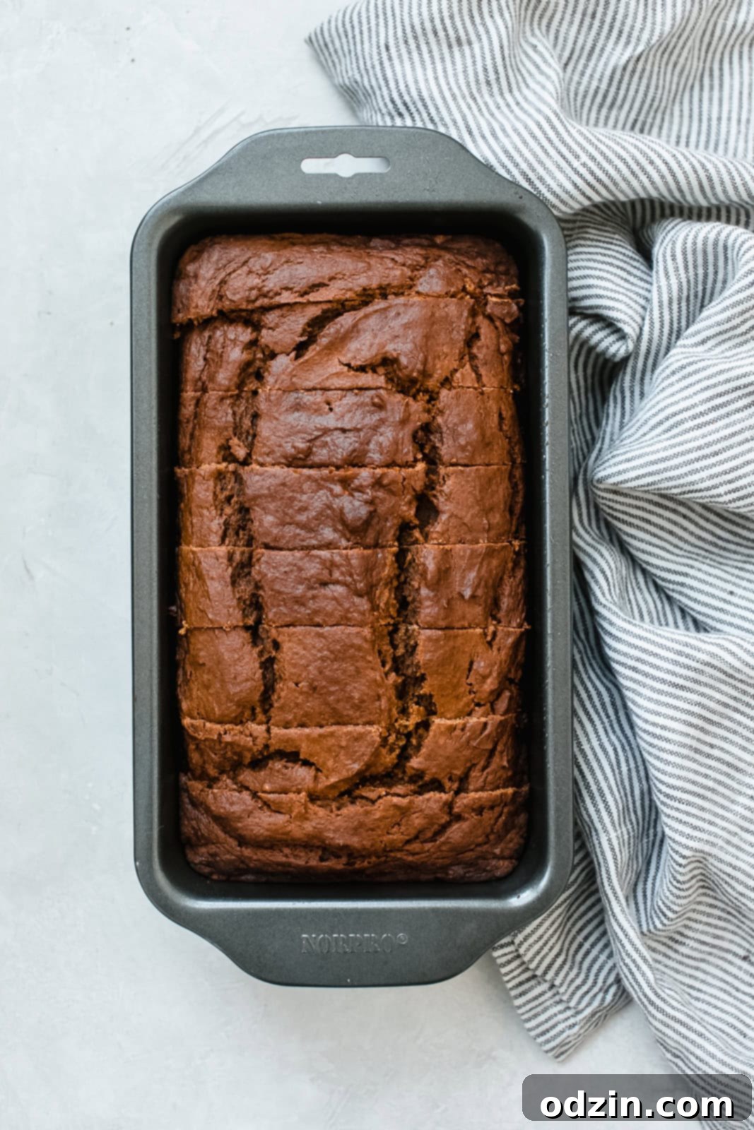 thick slices of brown butter pumpkin bread arranged in a loaf pan on a wire rack