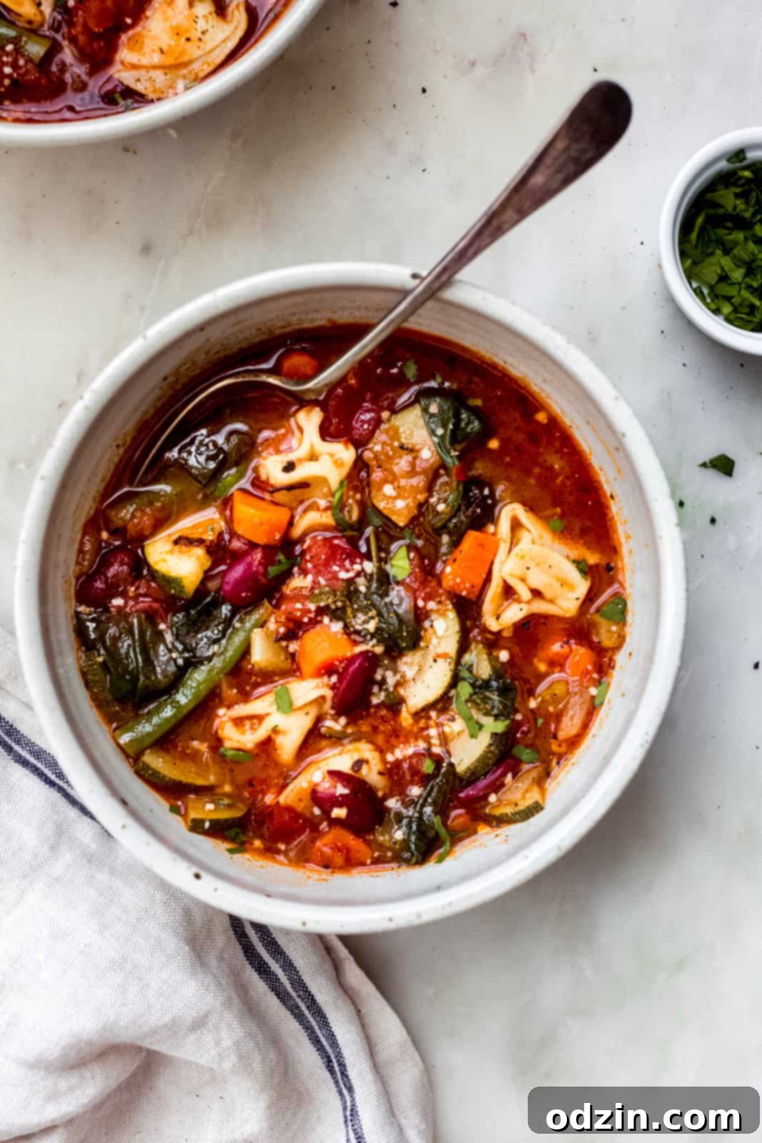 minestrone soup topped with grated parmesan cheese on white marble