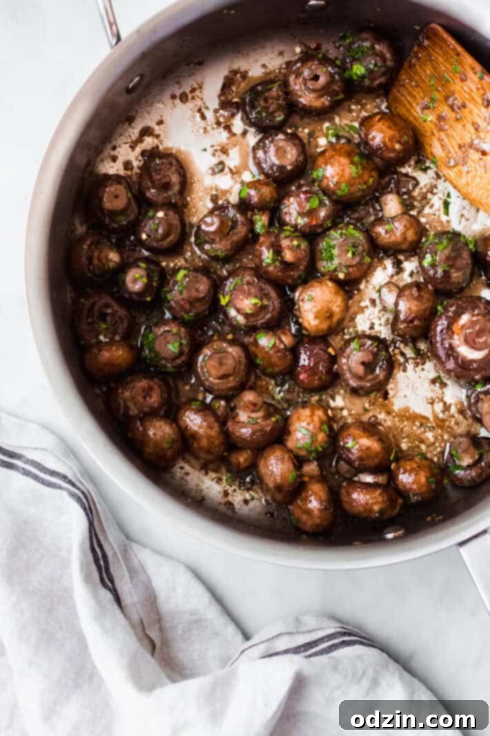 Sautéed garlic herb mushrooms in a skillet with a wooden spoon, ready to serve.