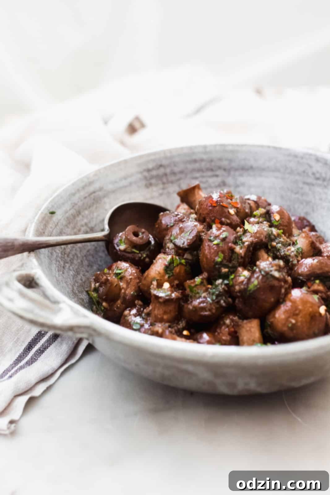 A bowl of freshly prepared sautéed garlic herb mushrooms, glistening with butter and herbs.