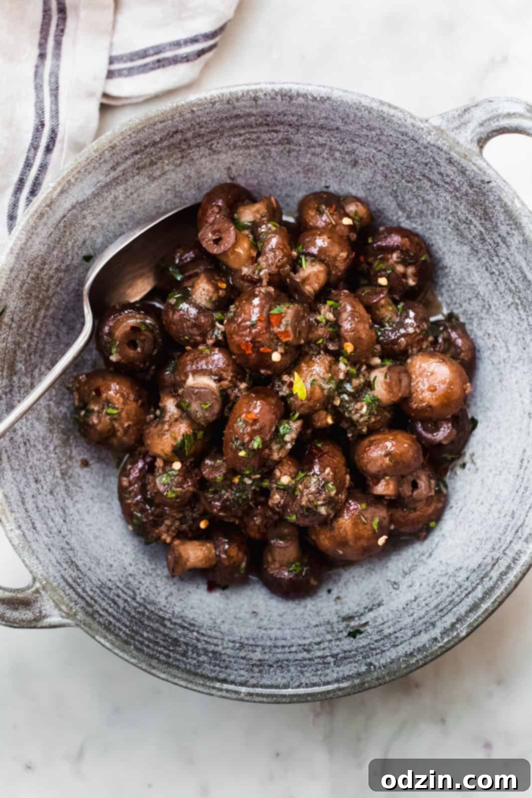 A top-down view of sautéed garlic herb mushrooms with fresh herbs and butter in a pan, ready to be served.