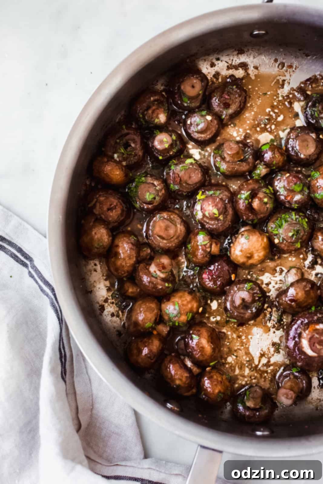 A sauté pan with perfectly cooked garlic herb mushrooms, infused with butter and seasonings.