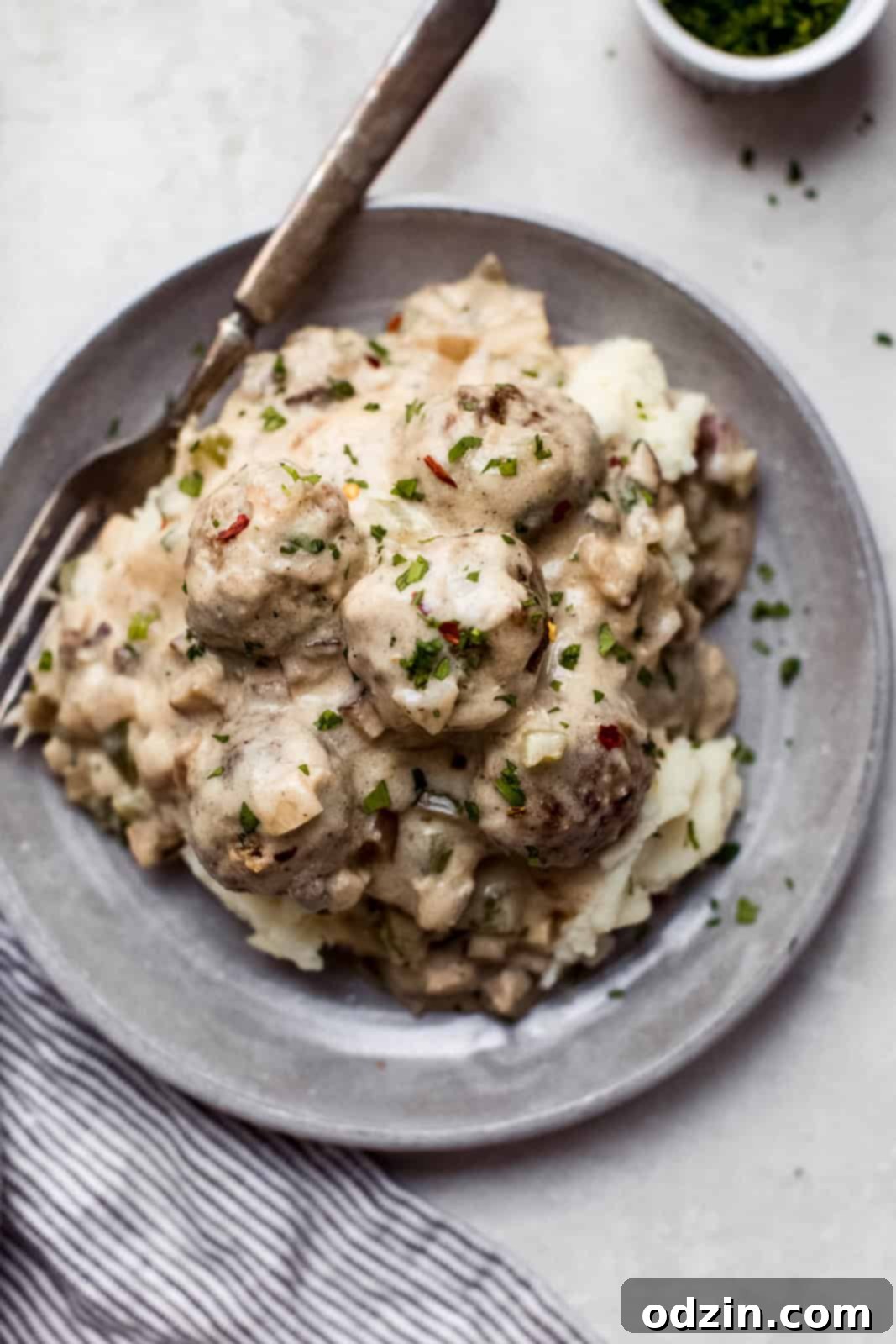 Philly Cheesesteak Meatballs with Creamy Garlic Cheese Sauce 8 plate with mashed potatoes topped with cheesesteak meatballs and cheese sauce