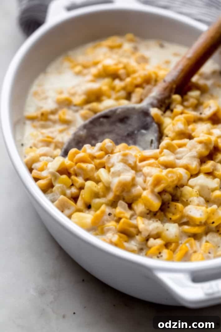 creamed corn in white dish with wooden spoon