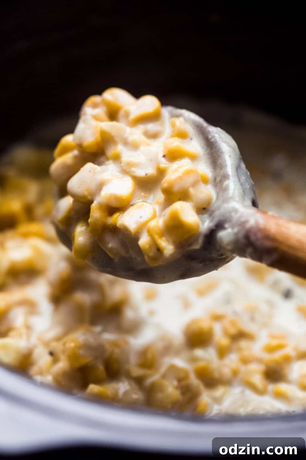 close up of creamed corn on wooden spoon