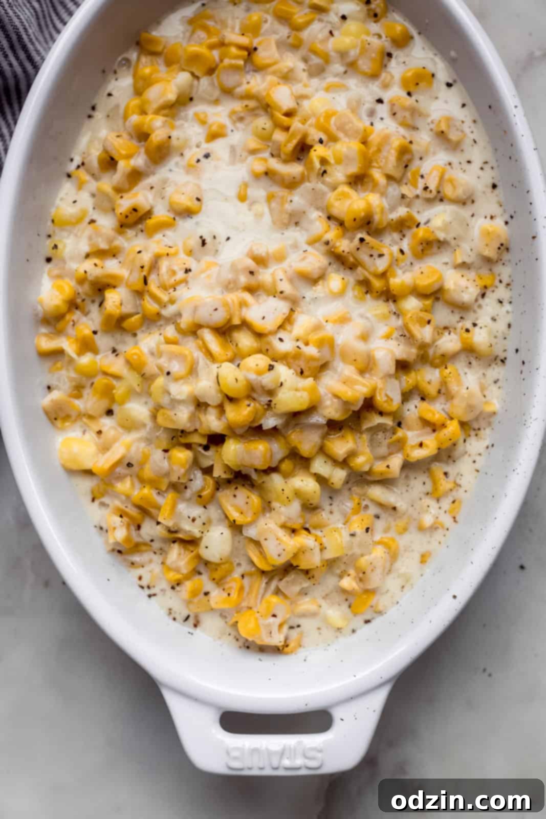 prepared creamed corn in white serving dish topped with crackers pepper