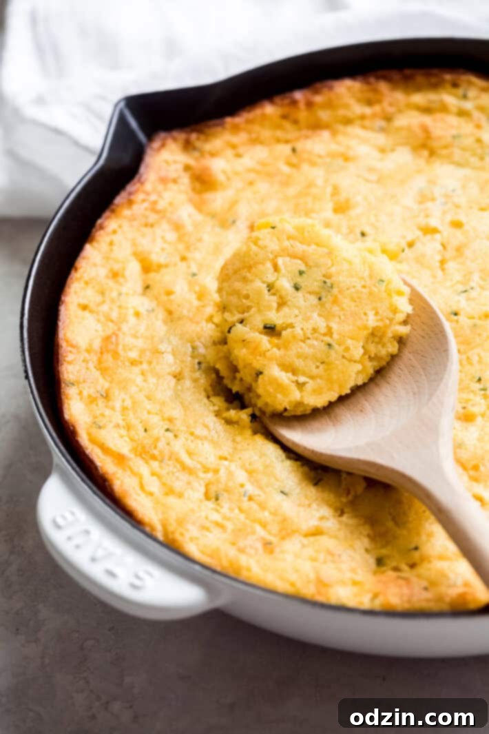 Creamy Corn Pudding with Garlic, Cheddar, and Chives - a quick and easy holiday recipe Close-up of the moist and fluffy texture of freshly baked cheddar chive spoonbread in a skillet.