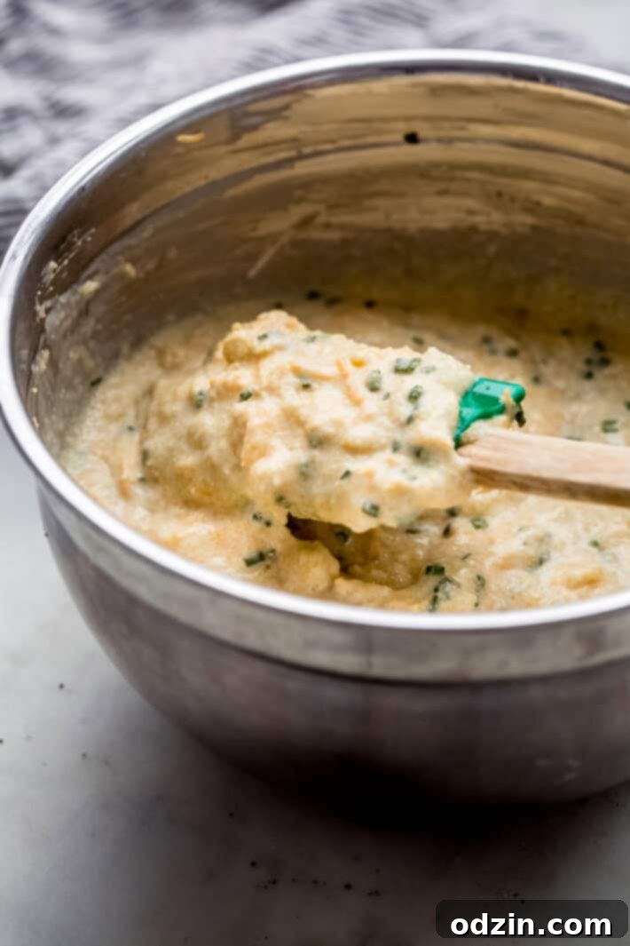 Unbaked Corn Pudding with Cheese and Chives - simple holiday recipe prep A baking dish filled with the unbaked garlic cheddar chive spoonbread mixture, ready for the oven.