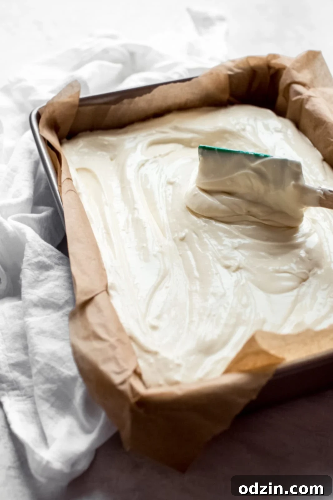 Spreading the cheesecake mixture evenly over the graham cracker crust in the baking dish