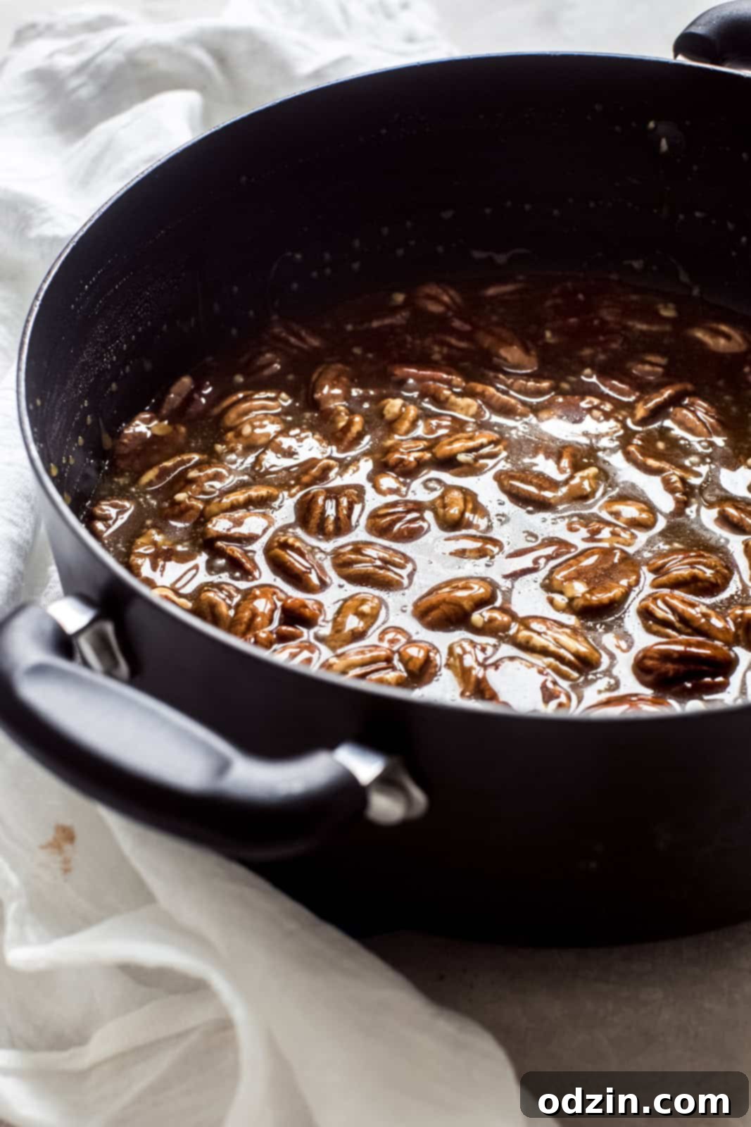Rich pecan pie topping mixture simmering in a black saucepan, ready to be poured