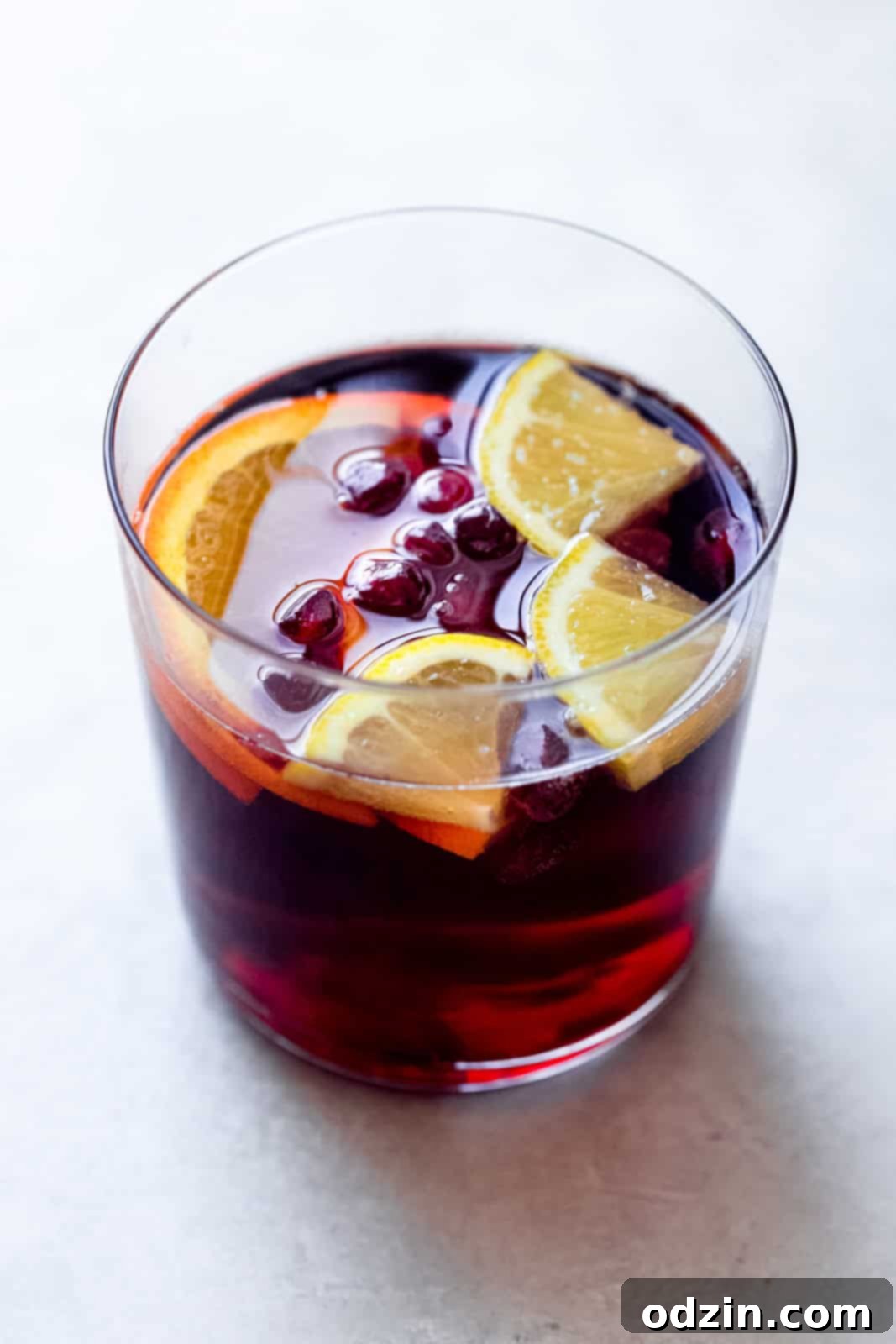 mocktail in glass on marble with lemon wedges and pomegranate arils in glass