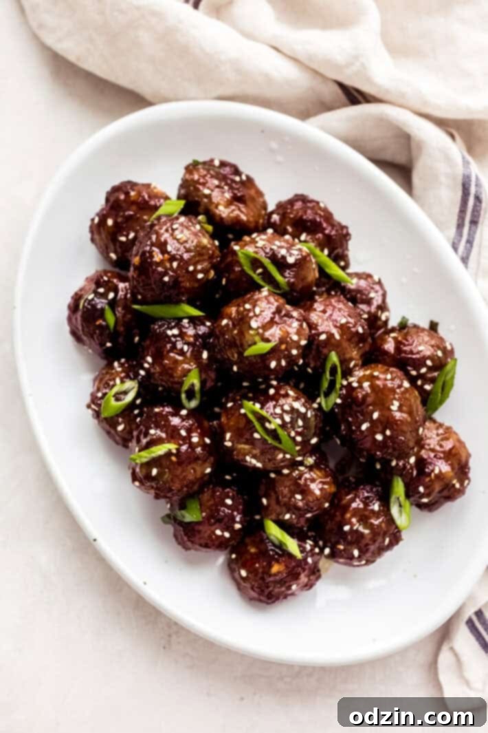 Sweet and Sticky Mongolian Beef Meatballs 2 prepared beef meatballs in Mongolian sauce on white oval dish
