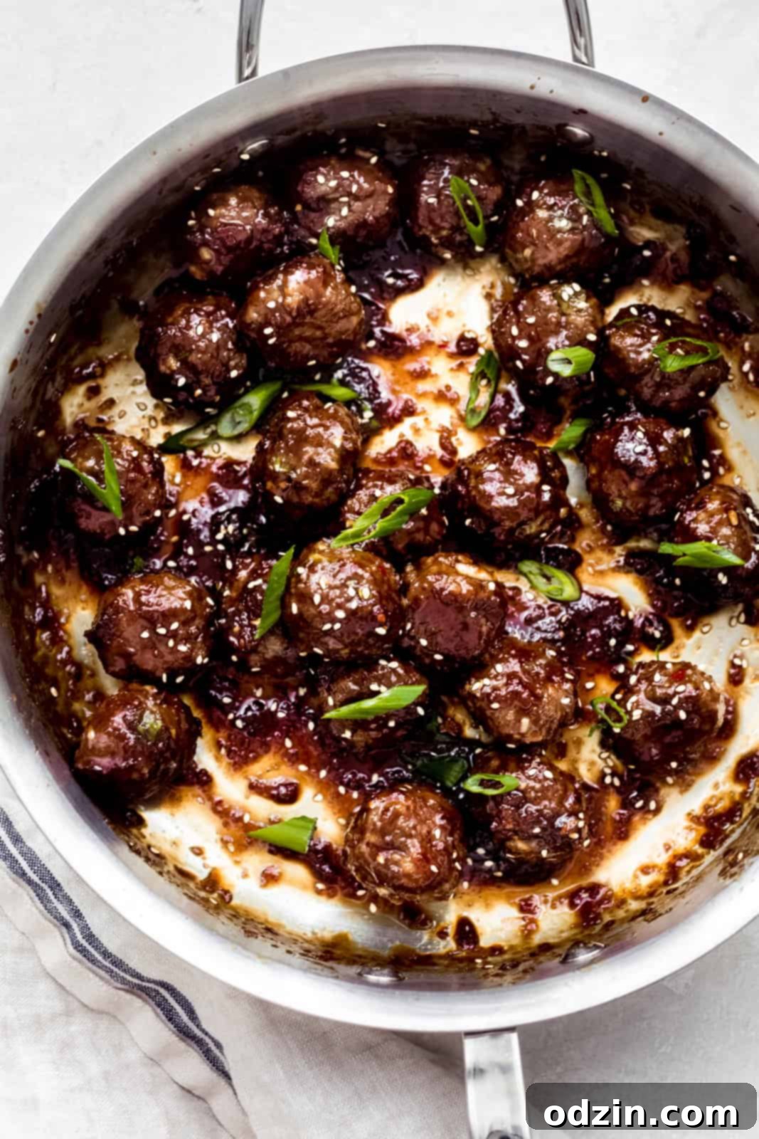 Sweet and Sticky Mongolian Beef Meatballs 8 sticky mongolian meatballs in steel pan topped with scallions and sesame seeds