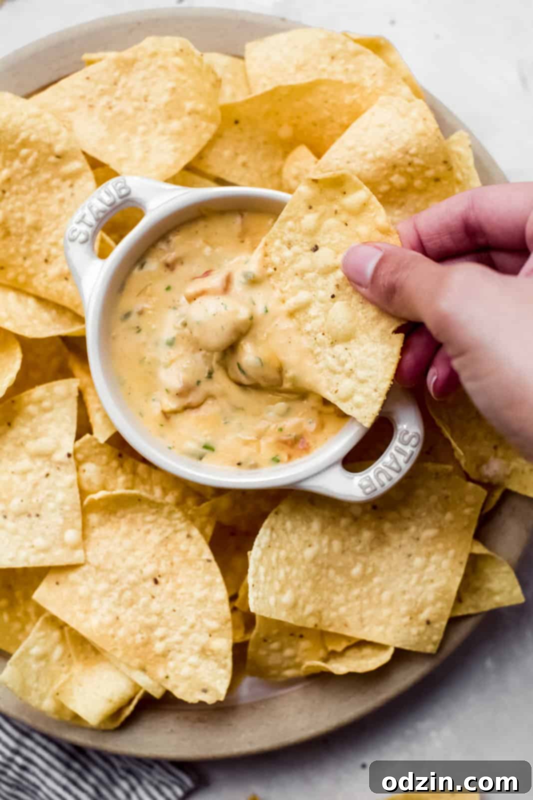 Zesty Texas Green Chili Queso 3 hand dipping dip in prepared Queso