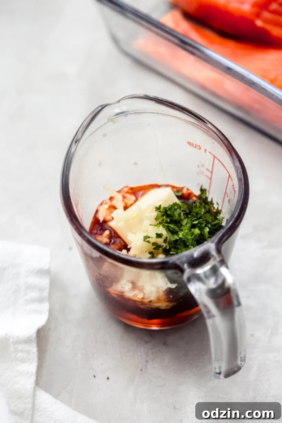 Ingredients for Honey Chipotle Sauce in a microwave-safe measuring cup: butter, garlic, chipotle, honey, and parsley