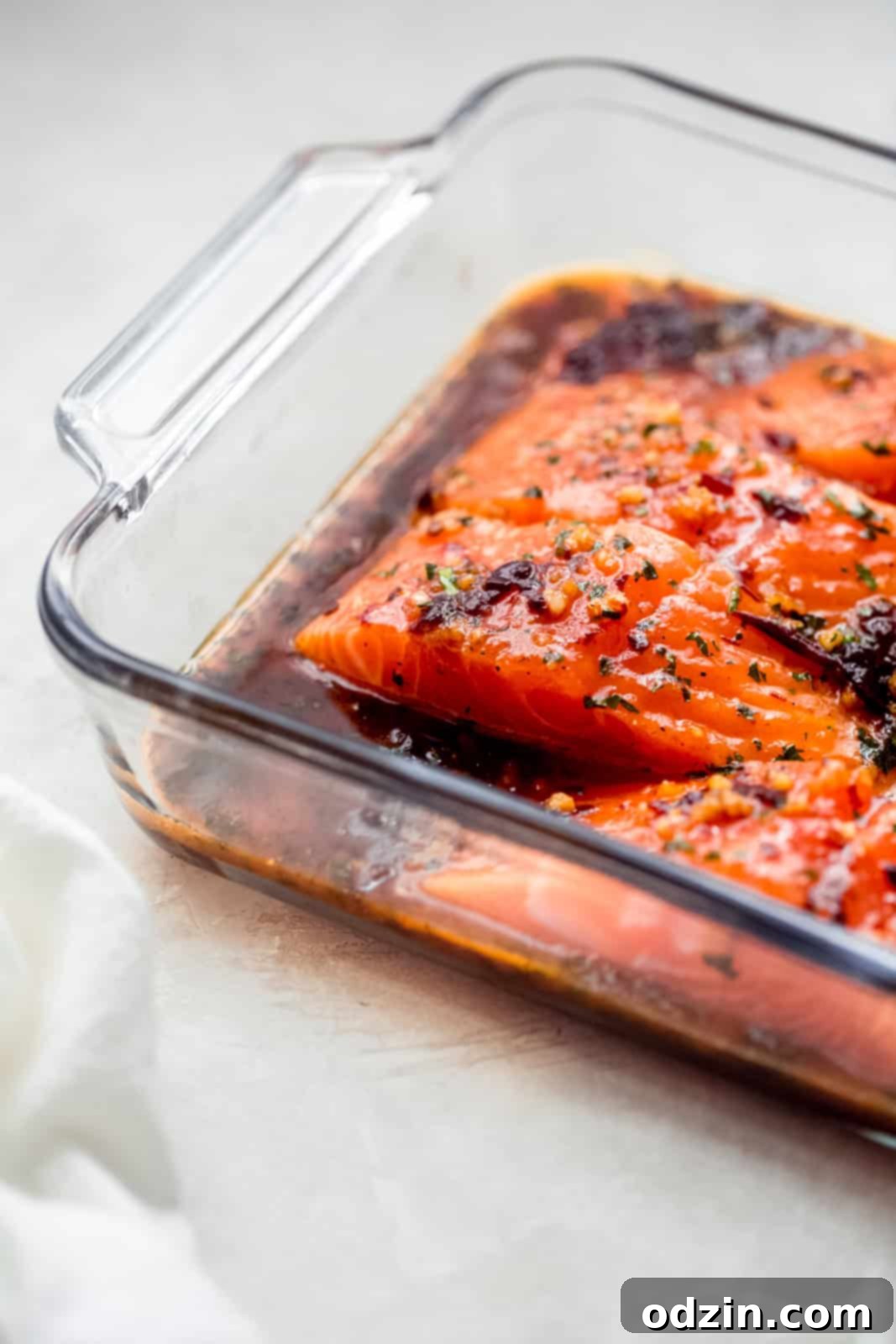 Salmon fillets marinating in the honey chipotle sauce in a glass baking dish, ready for the oven