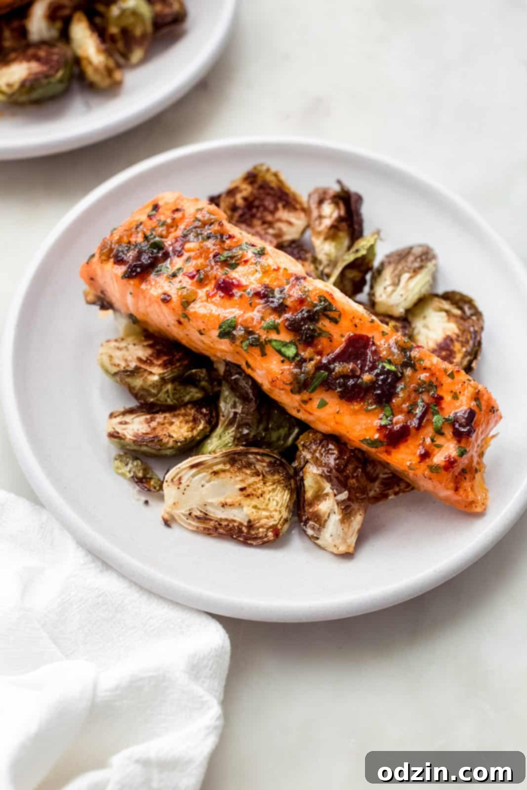 Baked Honey Chipotle Salmon served over roasted Brussels sprouts on a white plate