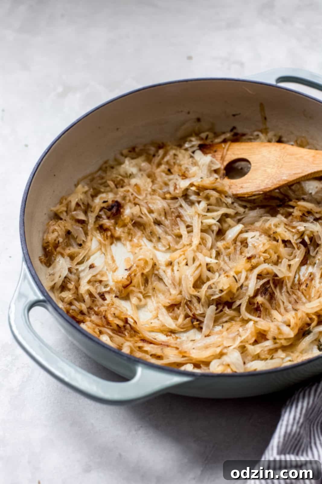 onions caramelizing in cast iron pan with wooden spoon