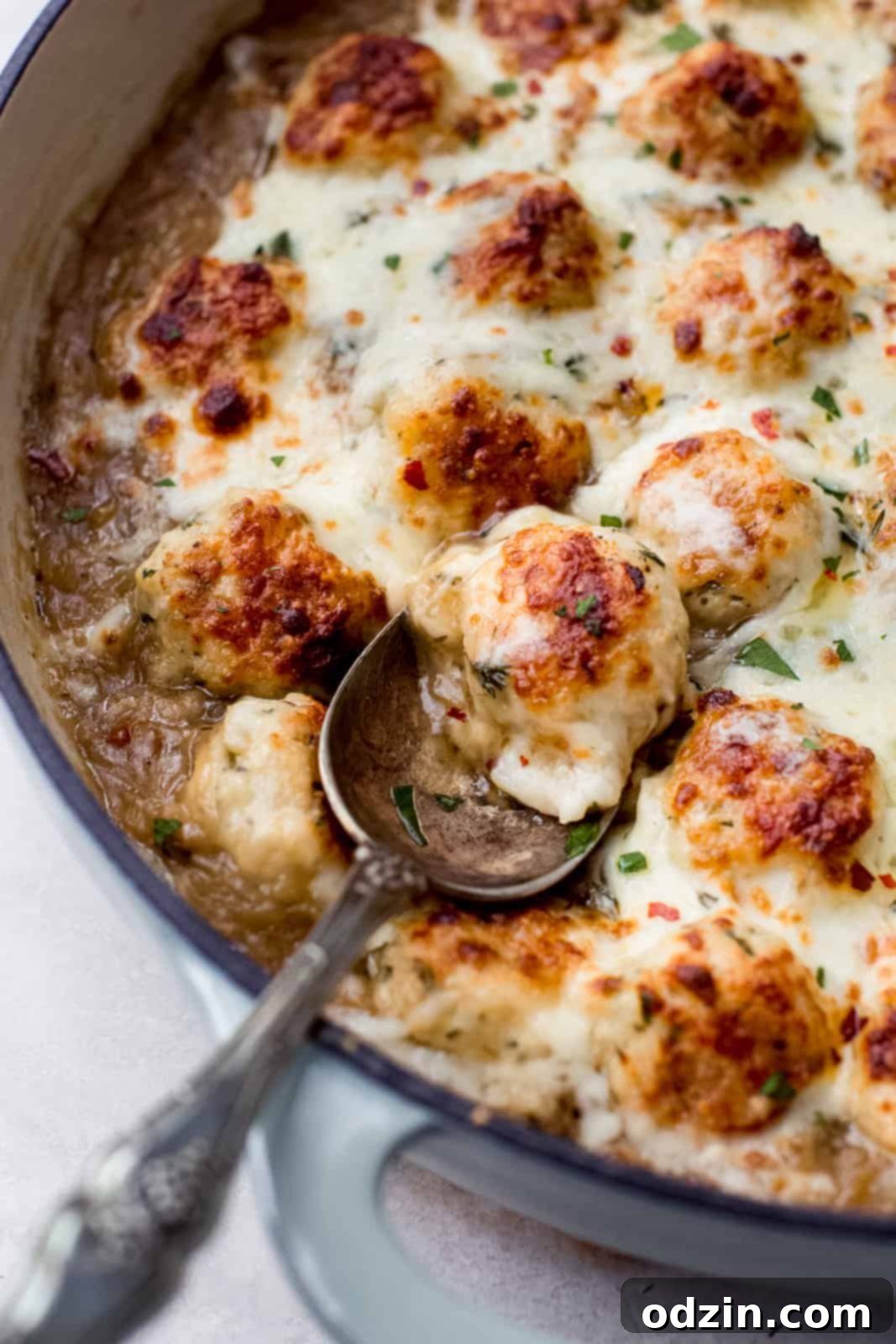 caramelized onion chicken meatballs with melted cheese on a metal spoon 
