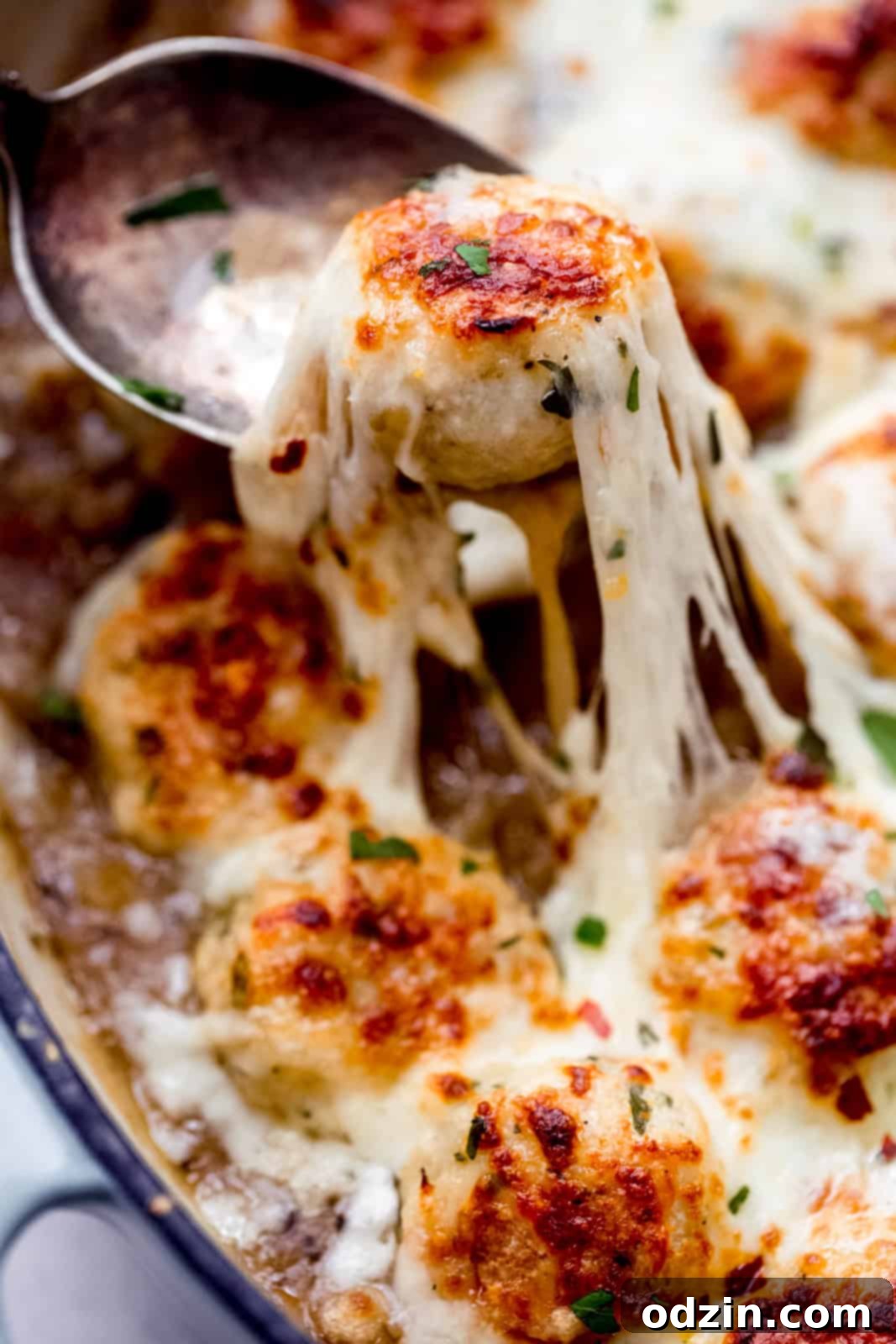 stretchy cheese on caramelized onion chicken meatballs on spoon