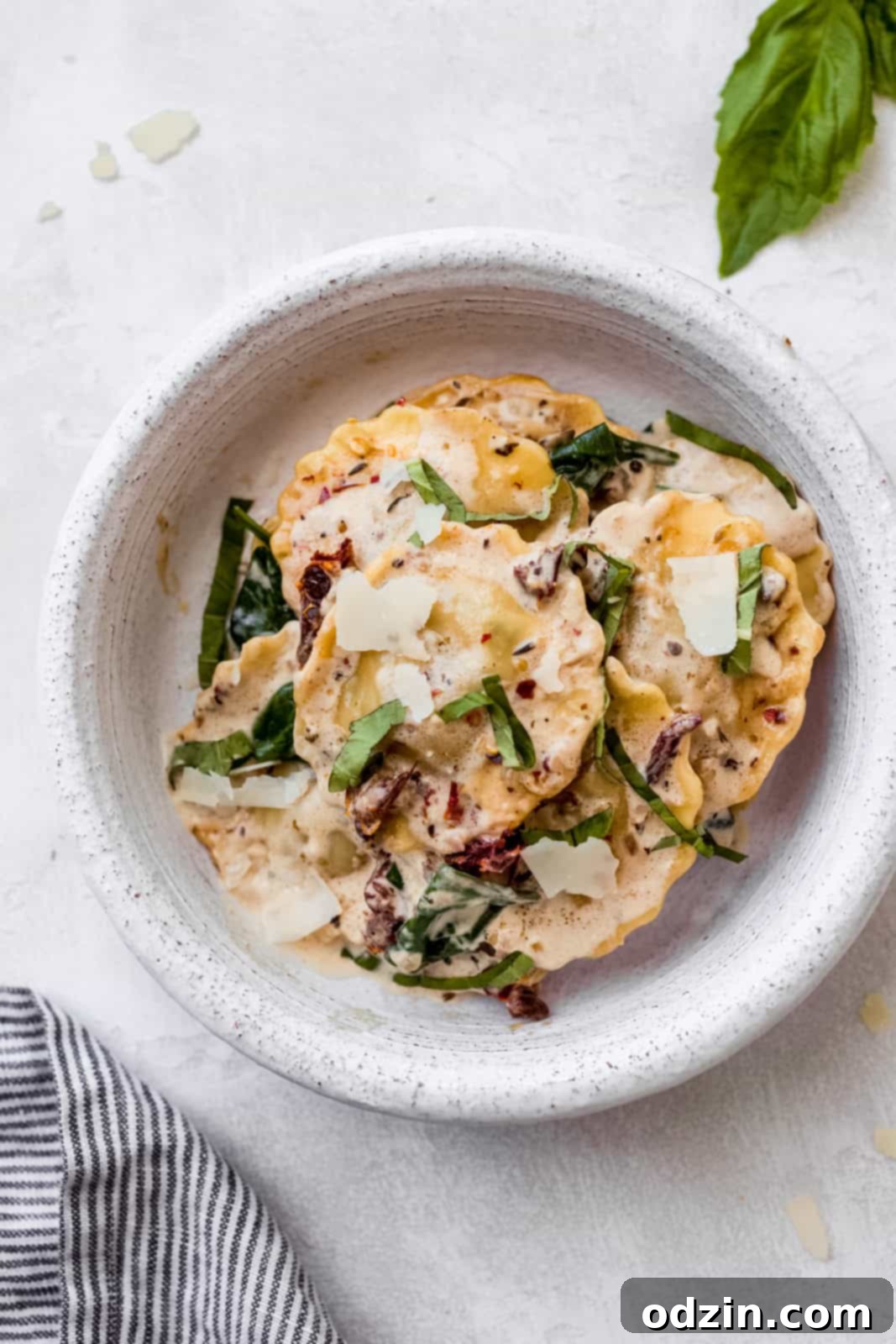 Creamy Tuscan Ravioli For An Unforgettable Date Night 5 prepared tuscan ravioli in a bowl topped with parmesan and basil