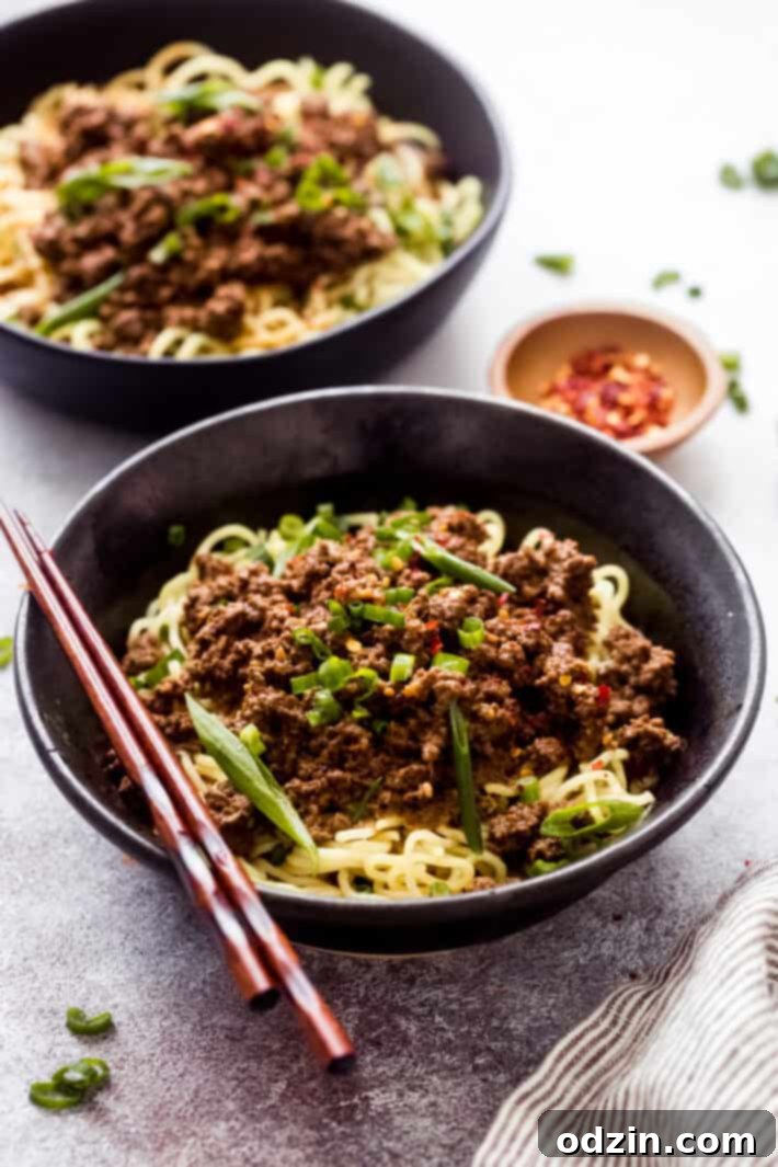 black bowl with noodles topped with dan dan mixture and chopsticks