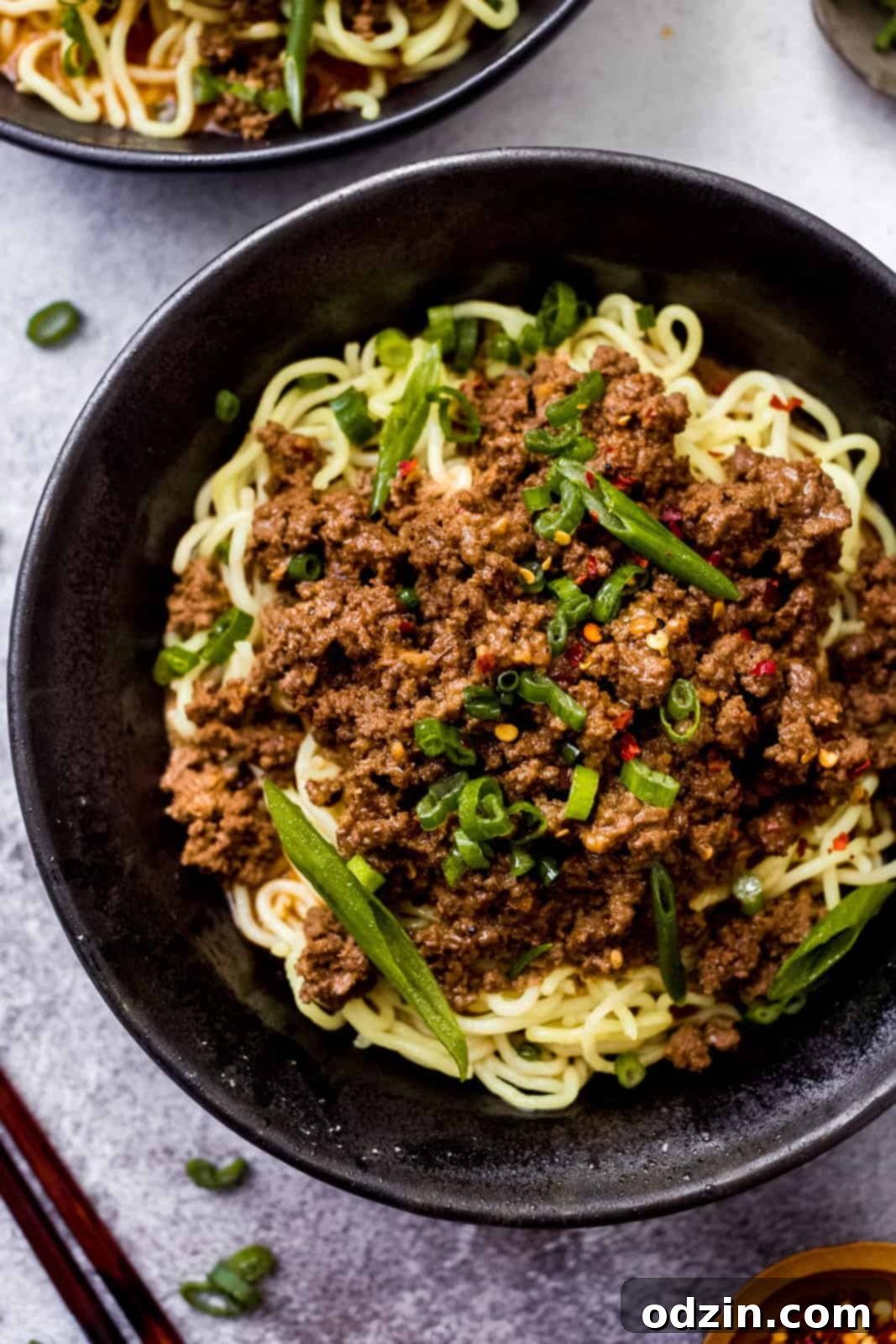 black bowl with dan dan noodles topped with scallions
