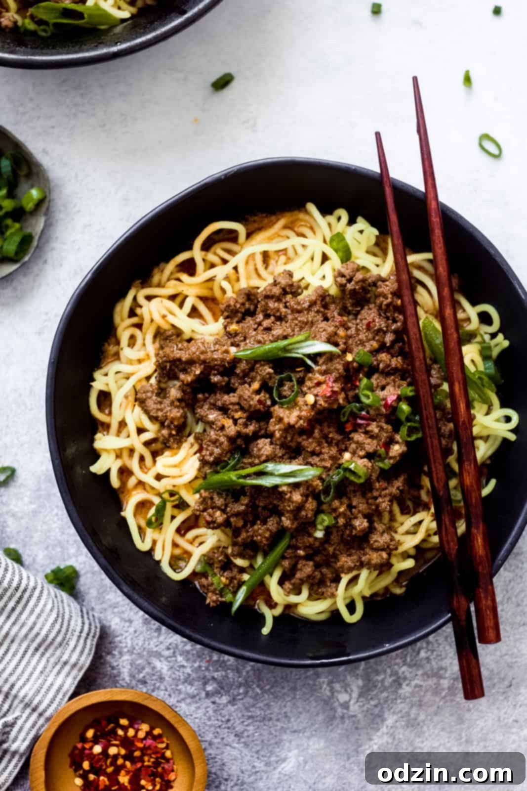 black bowl with chopsticks resting on top with noodles and meat mixture in bowl
