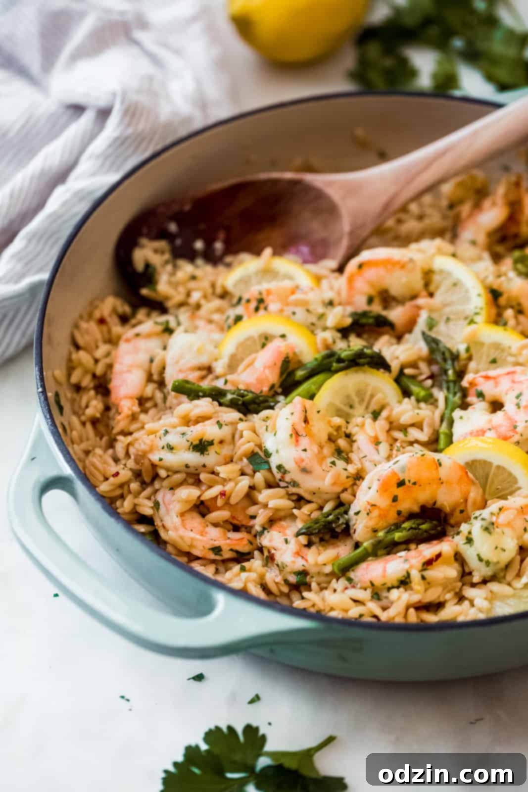 Orzo Shrimp Scampi with Asparagus side shot of cast iron shrimp scampi dish with wooden spoon