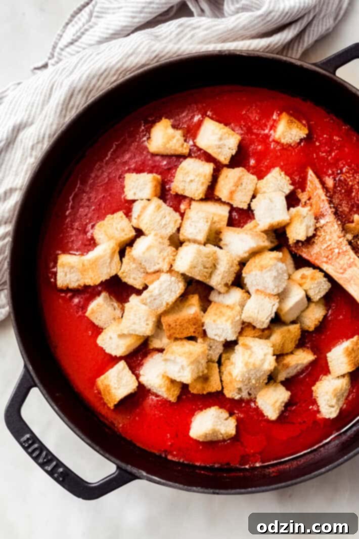 Adding toasted bread to Pappa al Pomodoro toasted bread on Pappa al Pomodoro soup in cast iron pot