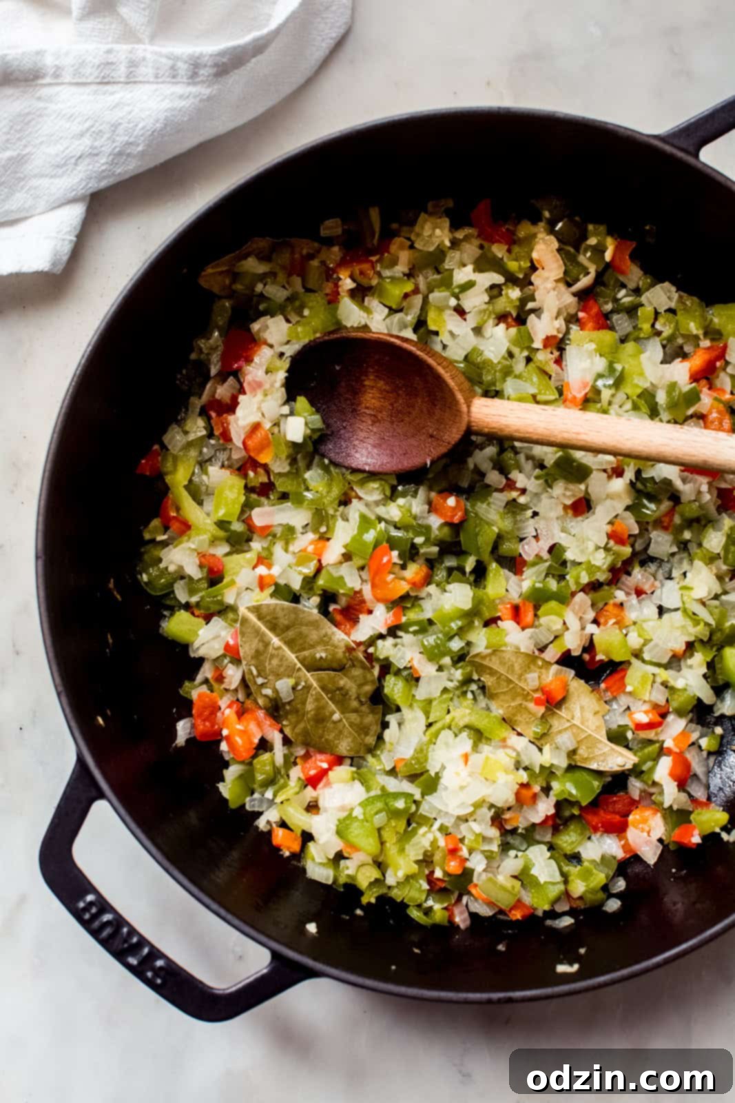 sautéed veggies in cast iron pot for black bean soup with wooden spoon