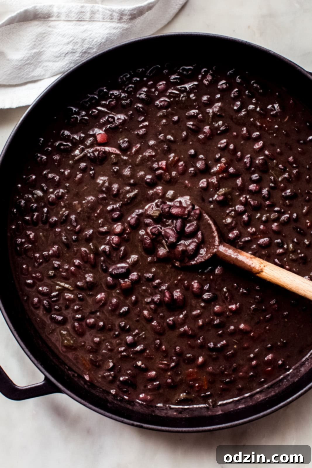 simmered cuban black bean soup in cast iron pot with wooden spoon