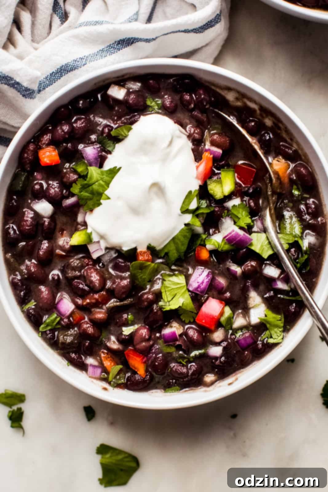 bowl of black bean soup topped with sour cream on marble