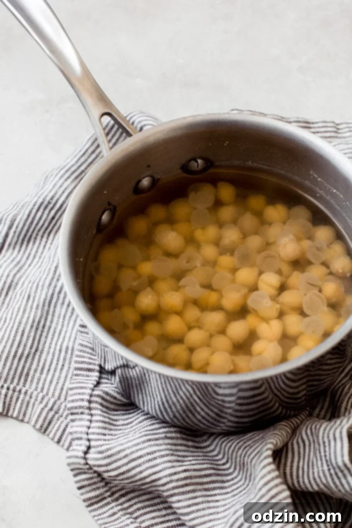 boiling chickpeas A close-up shot of chickpeas boiling in a saucepan on a stove, illustrating a key step in preparing ultra-smooth hummus.