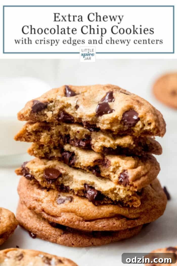 Ultimate Chewy Chocolate Chip Cookies 12 A stack of golden-brown chocolate chip cookies with two broken on top, revealing their warm, gooey chocolate centers, paired with a refreshing glass of milk.