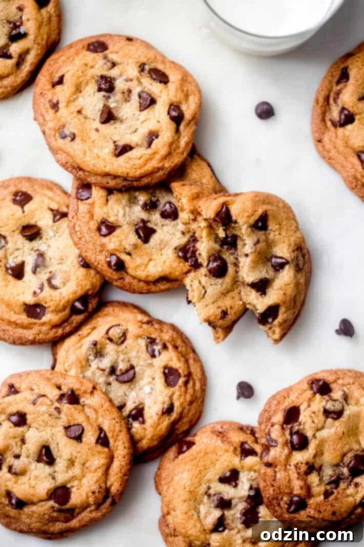 Ultimate Chewy Chocolate Chip Cookies 3 Two extra chewy chocolate chip cookies served with a glass of milk on a elegant marble surface.