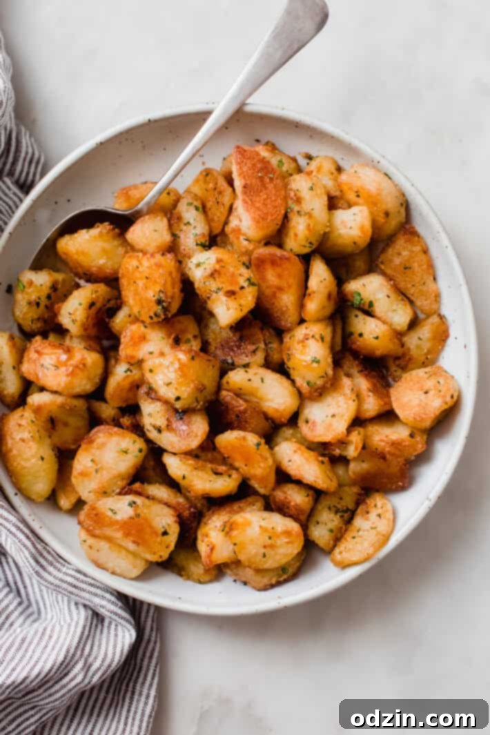 Crispy Garlic Oven Potatoes 9 top shot of roasted potatoes speckled with parsley in bowl with spoon