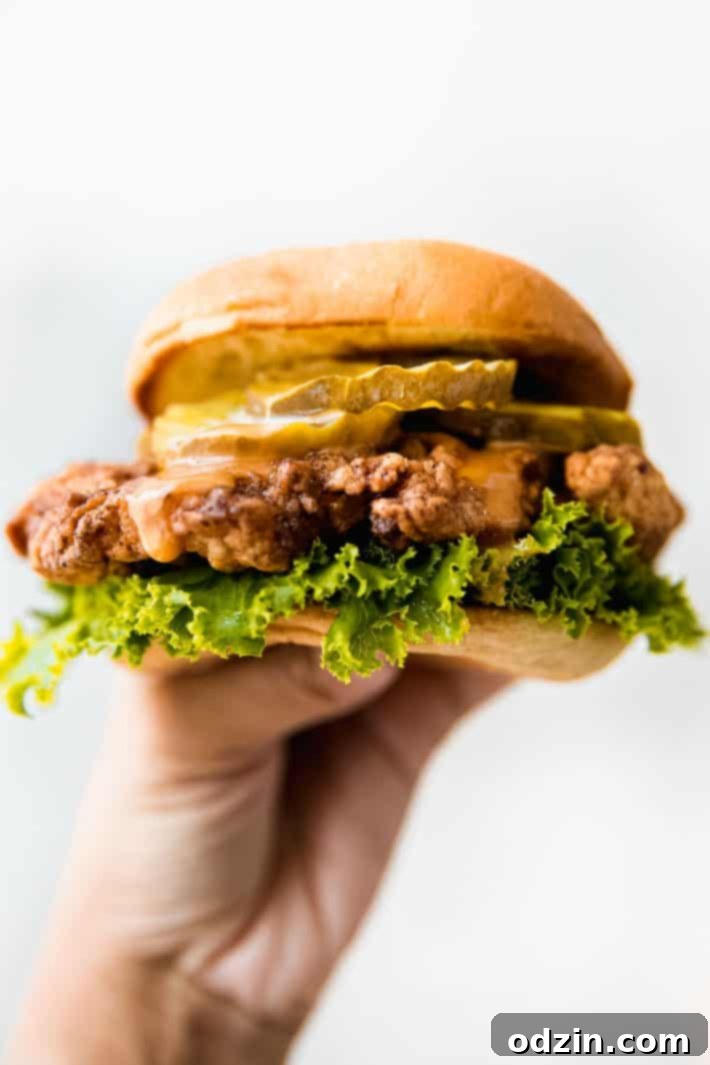 Signature Pickle Crunch Chicken Sandwich 7 Hand holding prepared crispy chicken sandwich