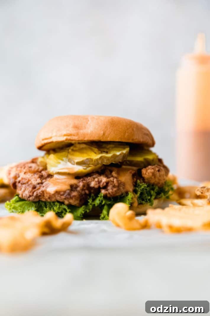 Signature Pickle Crunch Chicken Sandwich 9 Dressed sandwich on parchment paper with sauce bottle