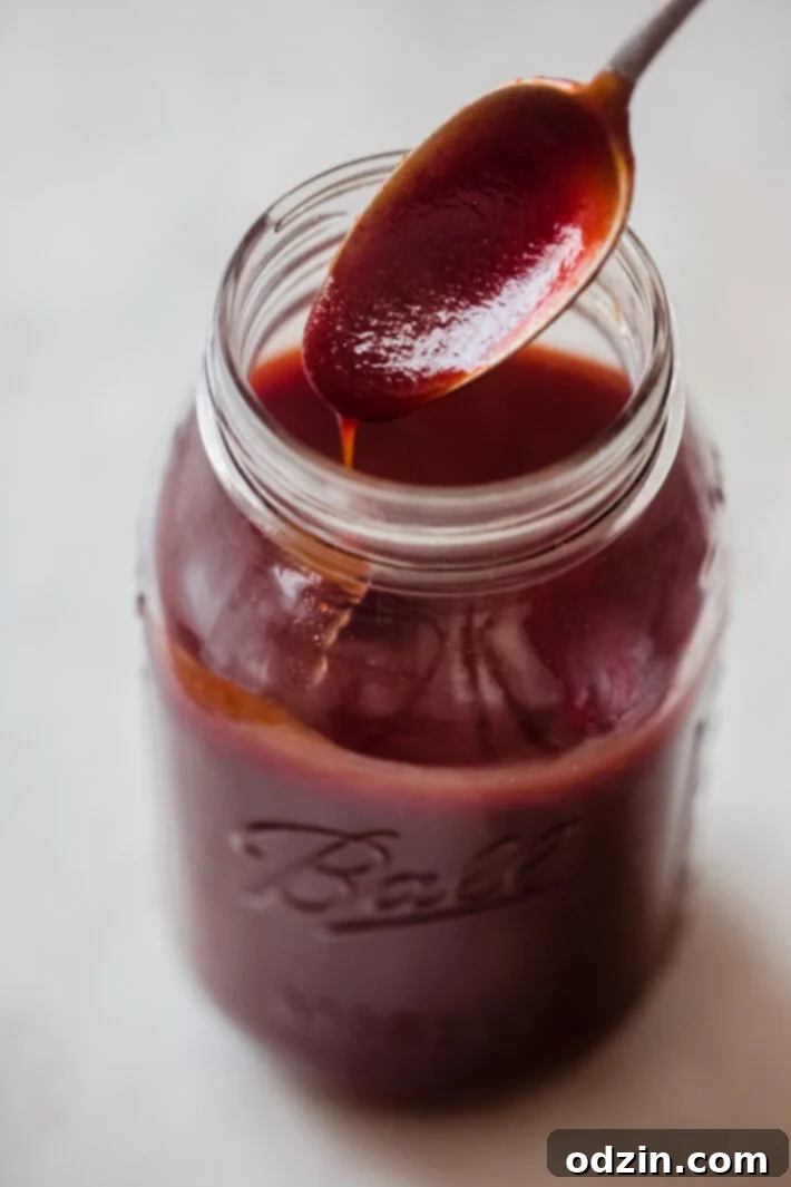 spoon lifting prepared bbq sauce out of mason jar