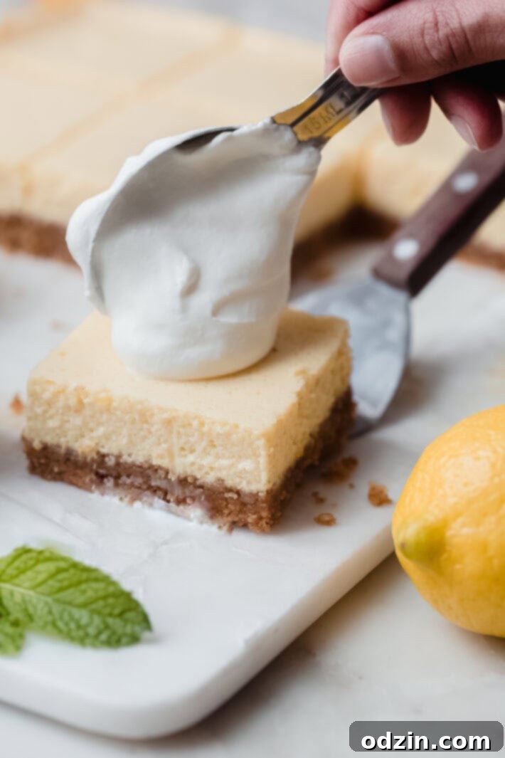 dollop of whipped cream dropping from tablespoon onto lemon bars