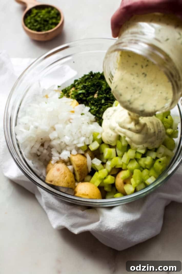 pouring sour cream ranch dressing into bowl with ingredients for potato salad