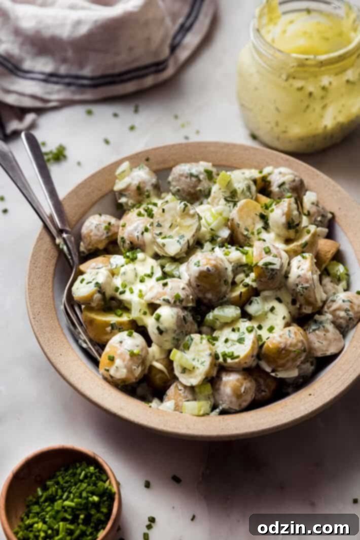 side shot of prepared potato salad in pottery bowl with rim with fork and spoon for serving