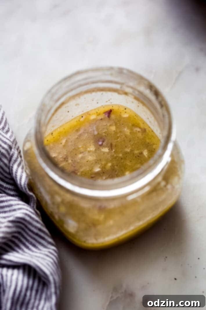prepared vinaigrette in mason jar on white marble with striped towel