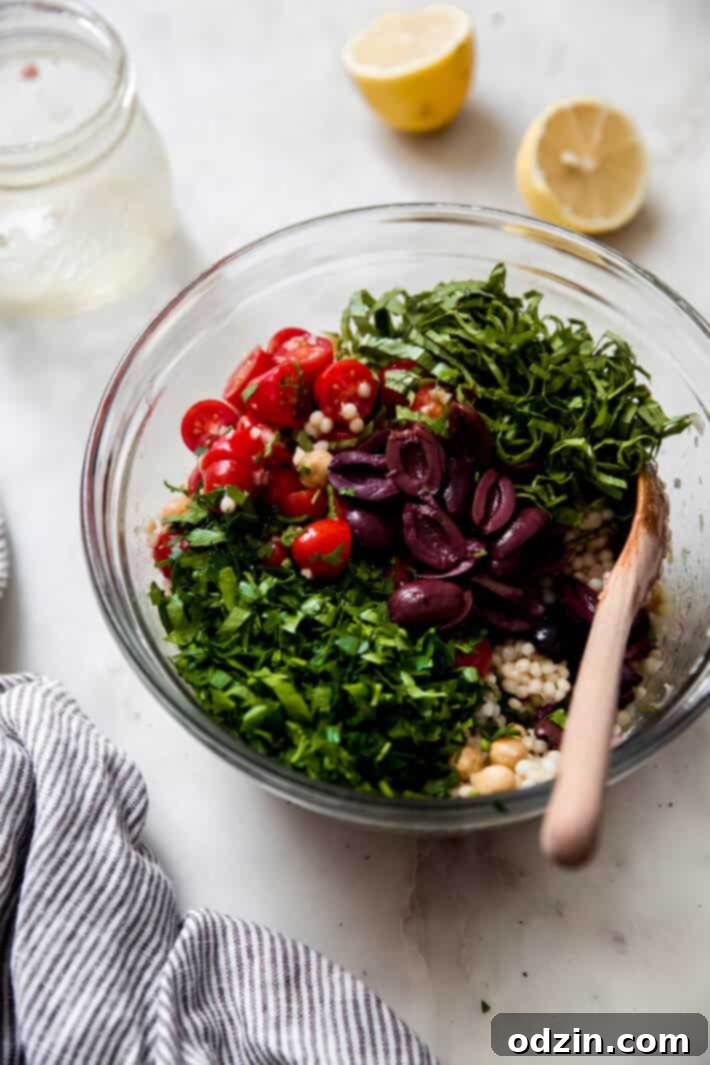 ingredients for couscous salad in glass bowl on white marble