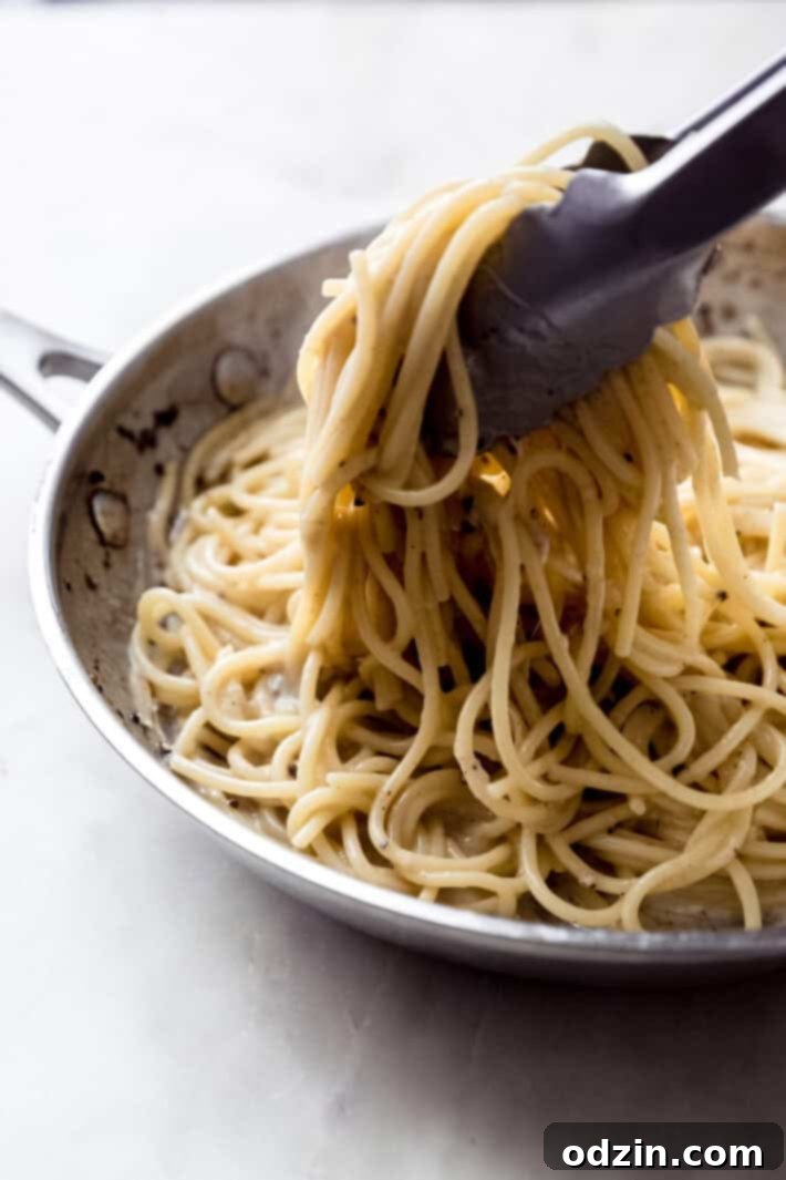 tongs lifting spaghetti from skillet