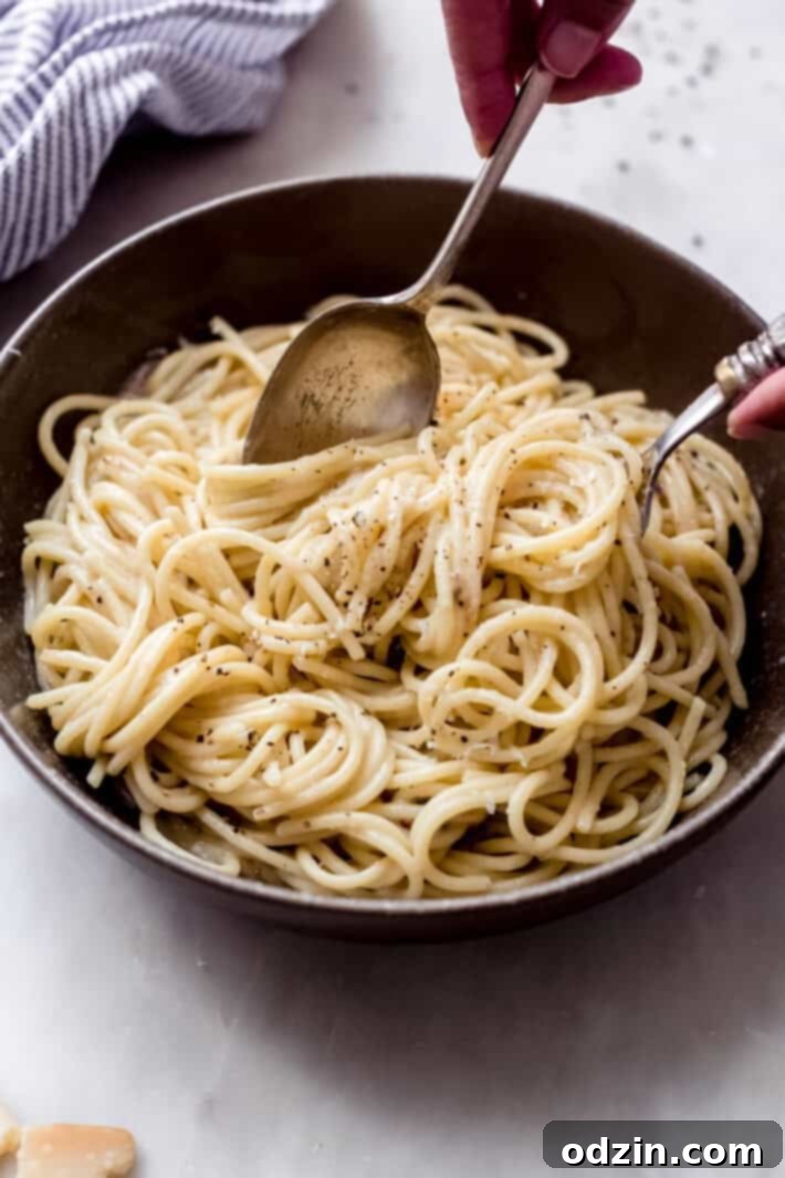 cheese and pepper sauce pasta in bowl with fork and spoon